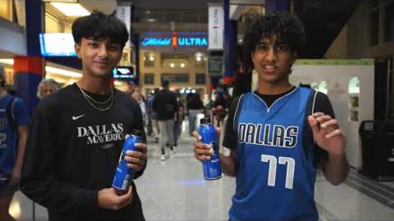 Two fans with Path Water bottles on the Mavericks arena concourse
